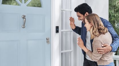 Ring Video Doorbell Wired in use on home with waving couple standing outside a locked blue door