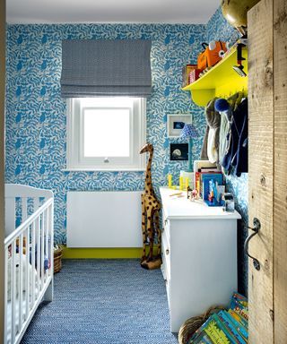 A baby boy nursery idea with blue floral wallpaper, white crib and yellow shelf.
