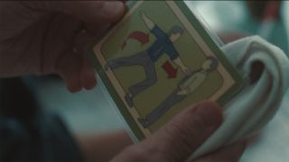 Mark holding a card showing two men opposing each other in Severance season 2