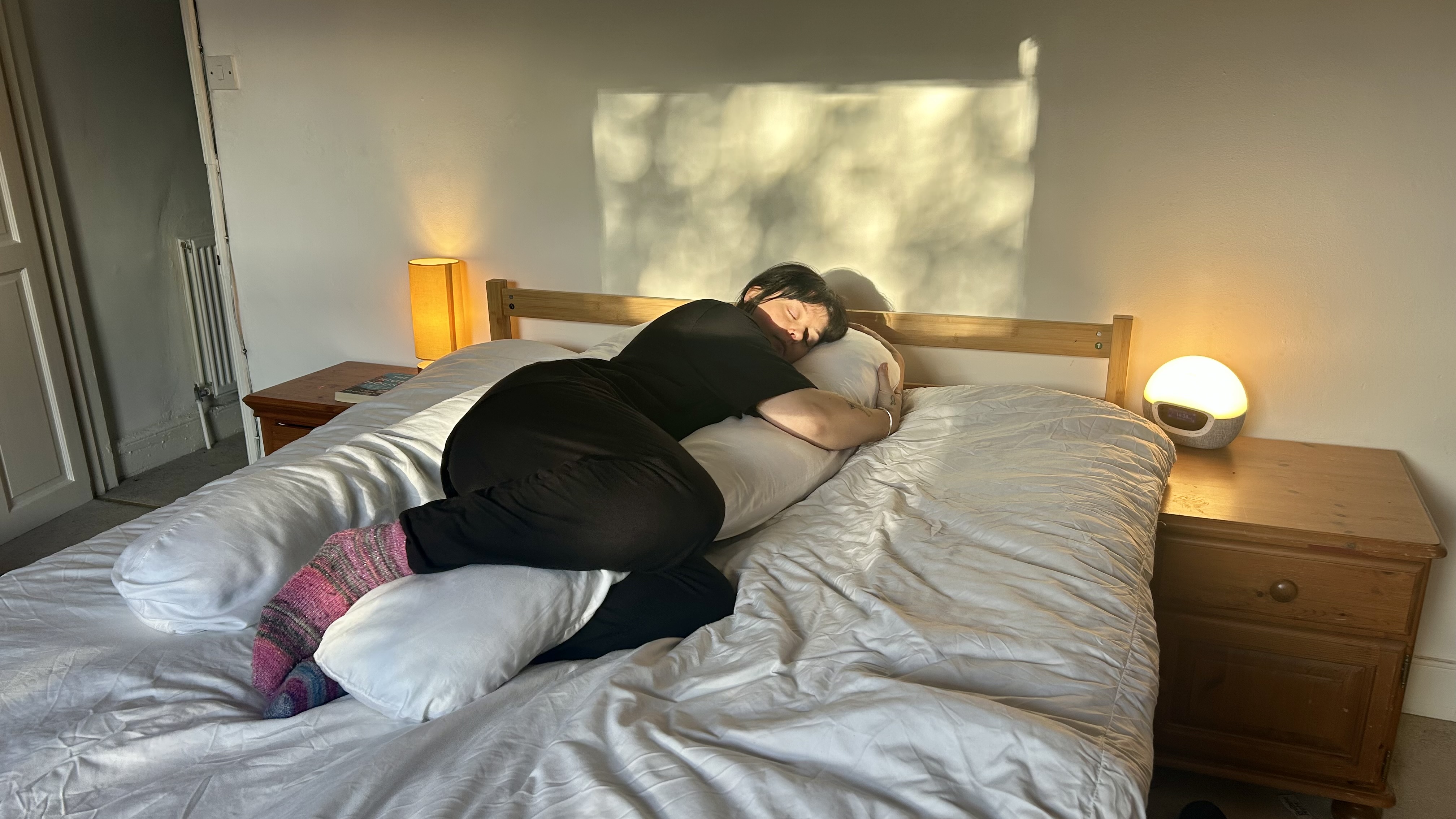 Tom&#039;s Guide Sleep Features Editor lying on her side using the Yana 360 Body Pillow