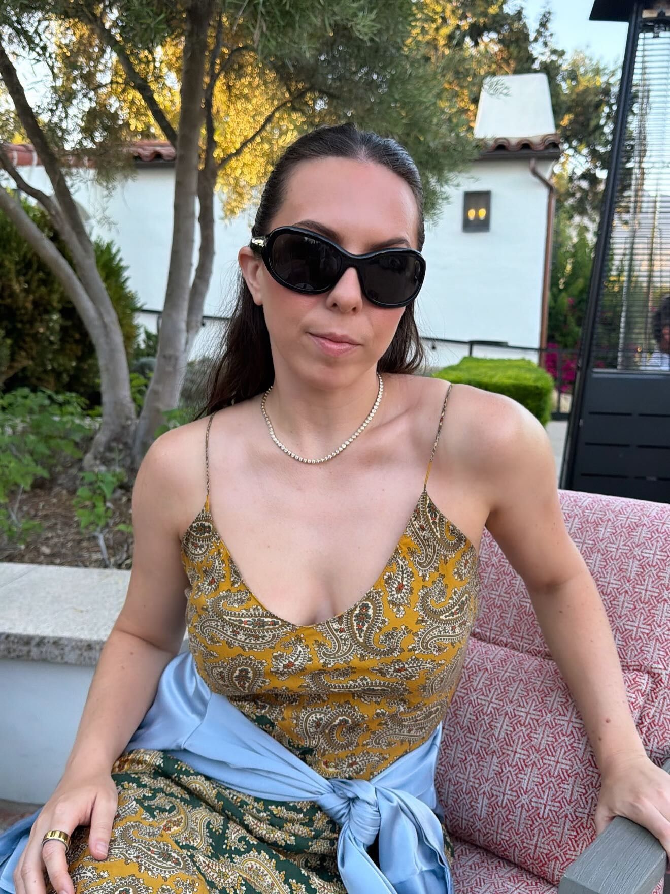 Lauren wears sporty black sunglasses and a patterned dress.