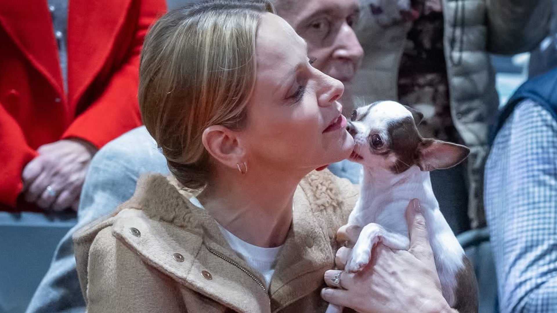 Princess Charlene holding a small dog licking her face