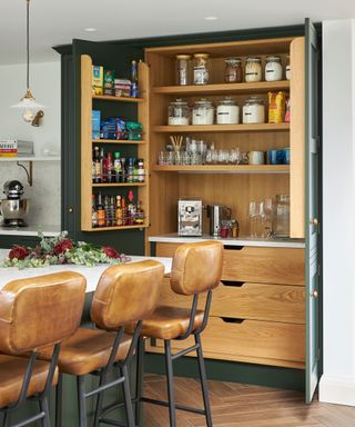 Carpenter-inspired kitchen with open wooden storage cabinet and brown leather chairs