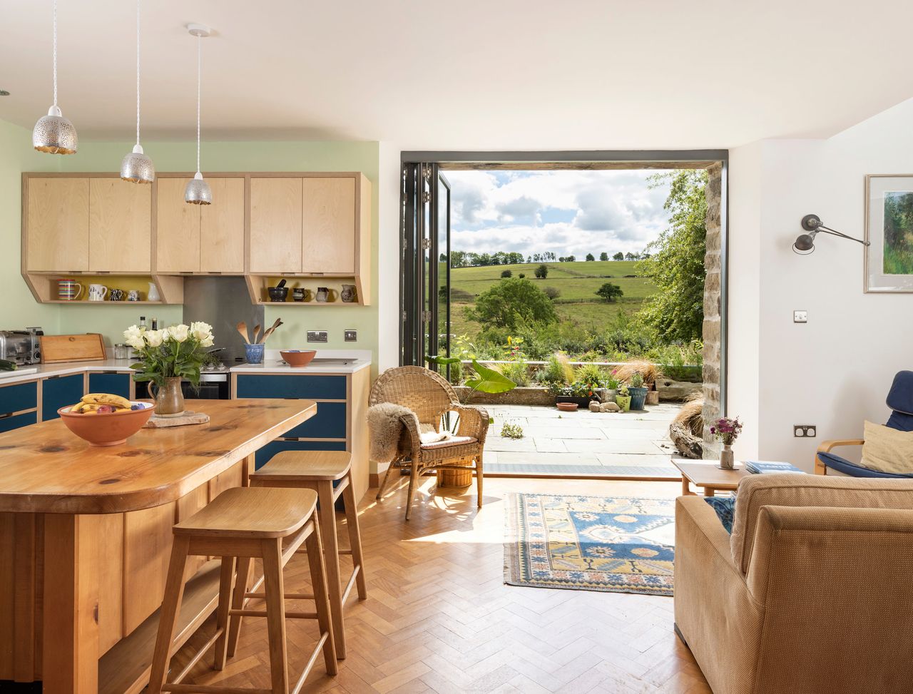 A barn conversion kitchen with bifold doors opening out onto the countryside