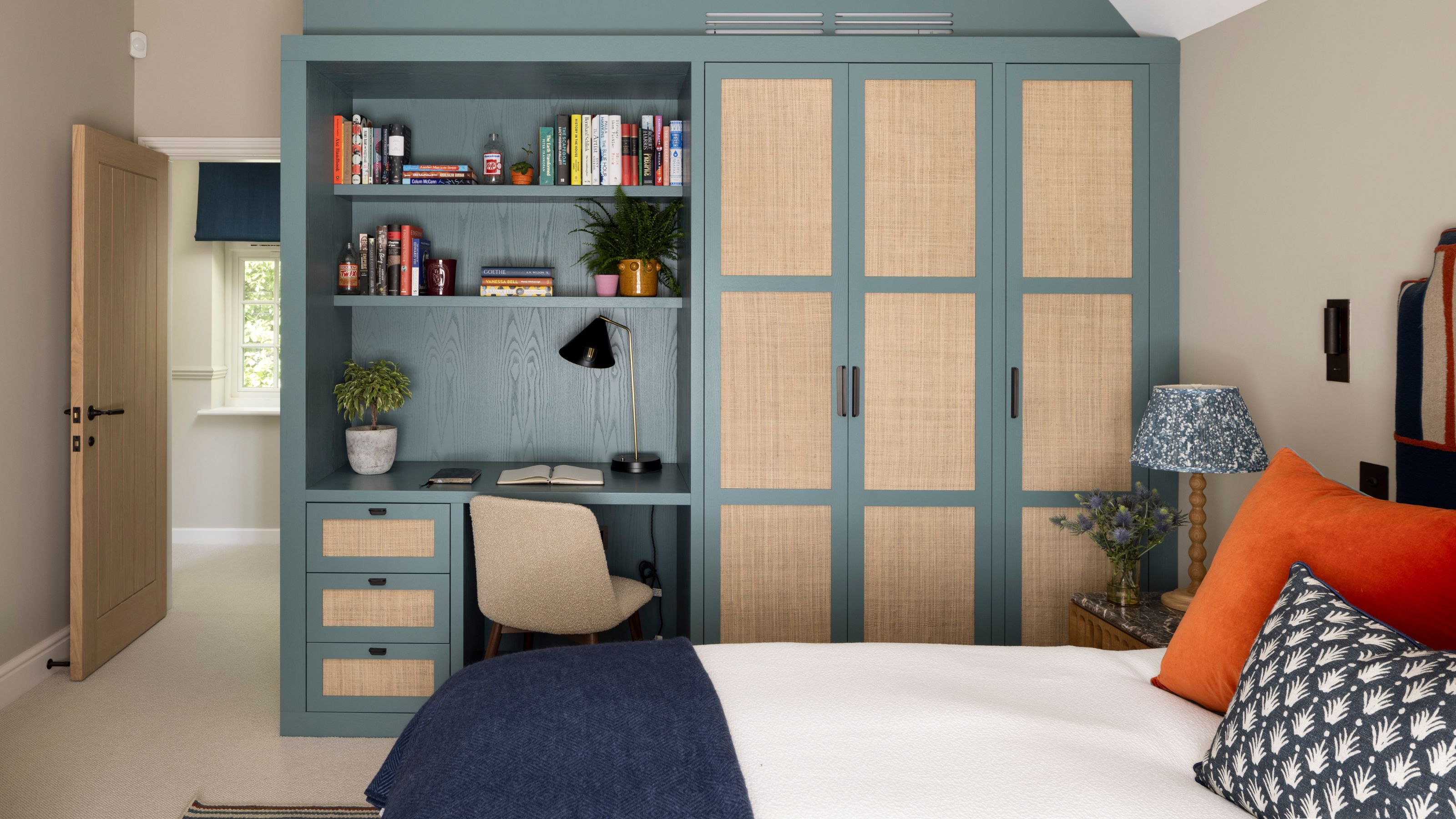 a neutral kids bedroom designed with custom wardrobe and built-in desk area painted blue with woven panels