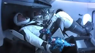 NASA astronaut Bob Behnken and the Demo-2 0-g indicator, a small stuffed dinosaur, after launch on May 30, 2020.