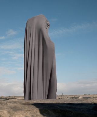 A person wrapped in gray fabric.