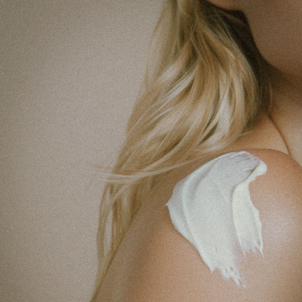 a close up of a woman's shoulder with cream on it