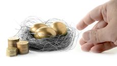 A hand reaching for golden goose eggs in a bird nest next to a stack of gold coins