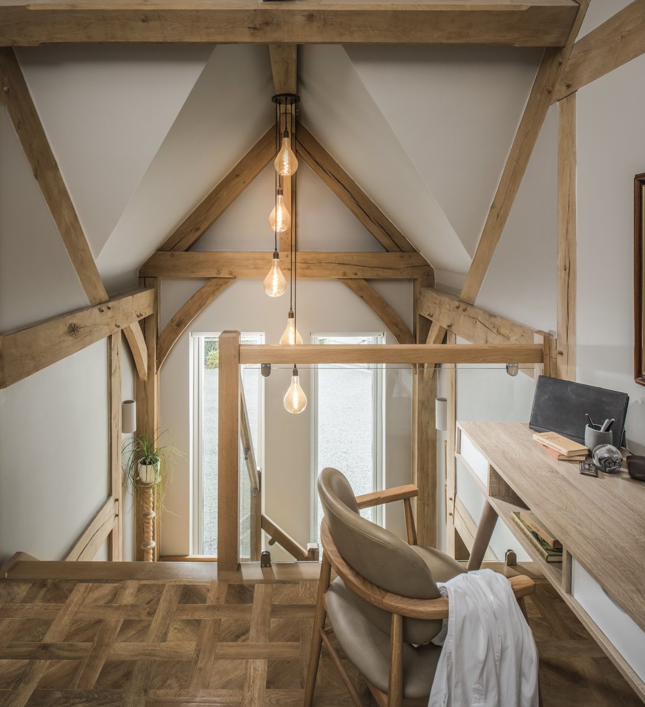 The interior of an oak frame home with a vaulted ceiling and a small office setup on the first floor landing