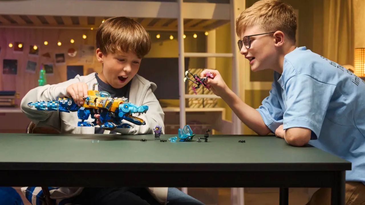 Two children play with a Lego robot crocodile and figures on a table