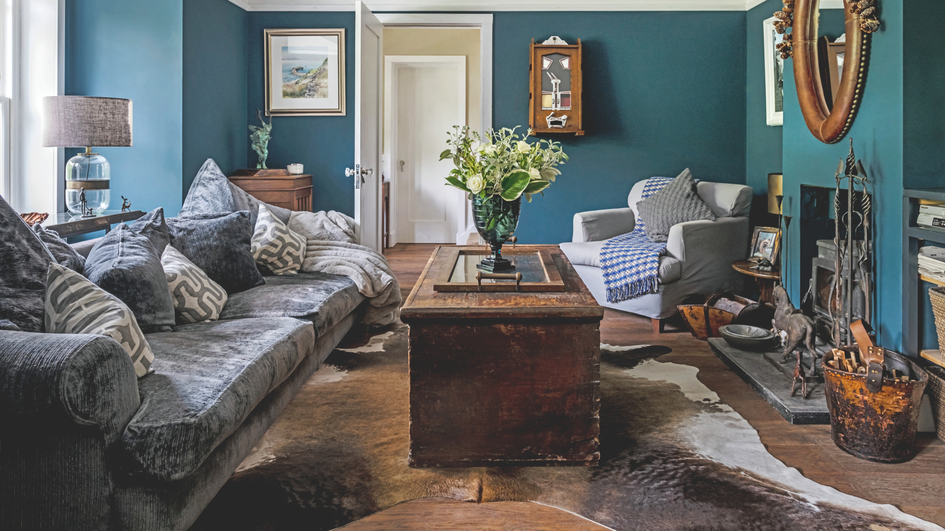 iving room with wooden floorboards, white walls, grey wainscoting and light grey sofas. New England Style renovation.
