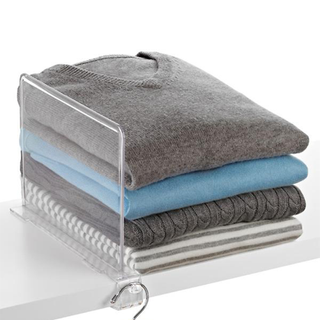 A clear acrylic shelf divider and neatly stacked sweaters