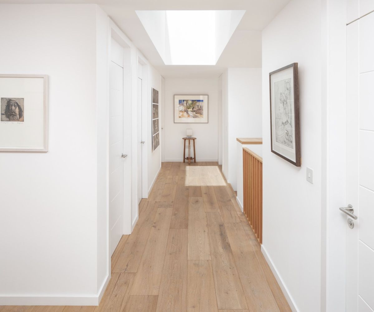 An upstairs corridor in a modern home with white walls and a skylight