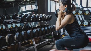 Woman performs squat with dumbbells in rack position