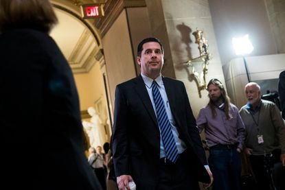 Devin Nunes walks through a hallway flanked with reporters.