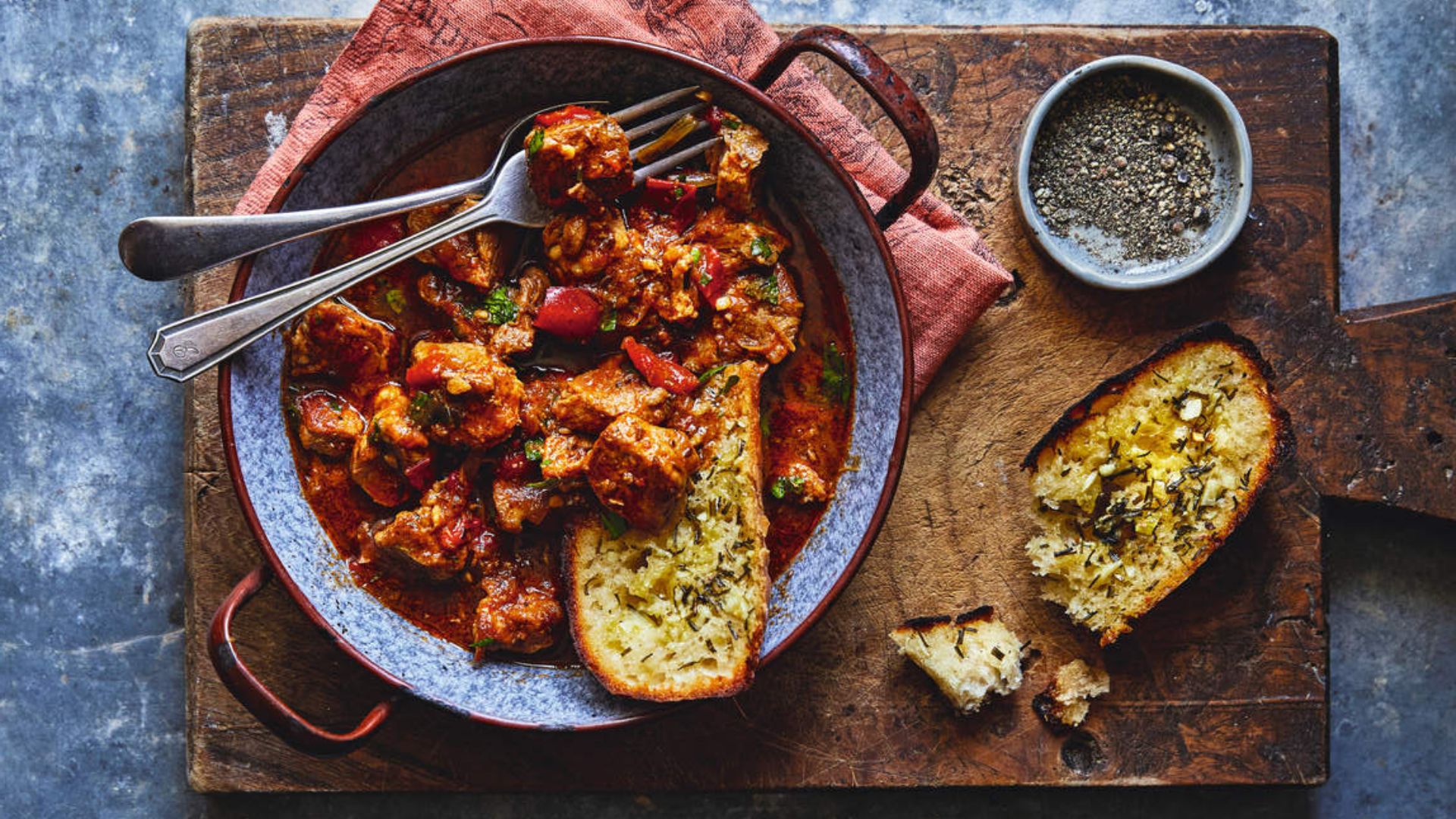 Pork goulash on a wooden board with garlic bread