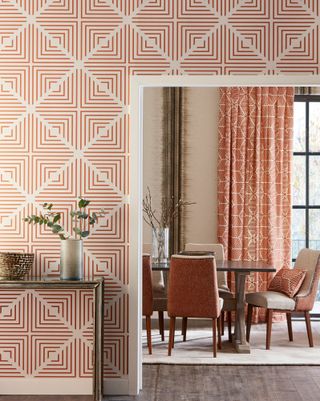 View into dining room with red and white geometric patterned wallpaper and a complementary curtain fabric