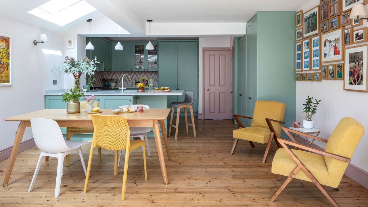 Light green coloured kitchen with dining and seating area with yellow armchairs