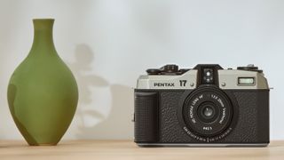 Pentax 17 on a wooden surface, next to a green vase