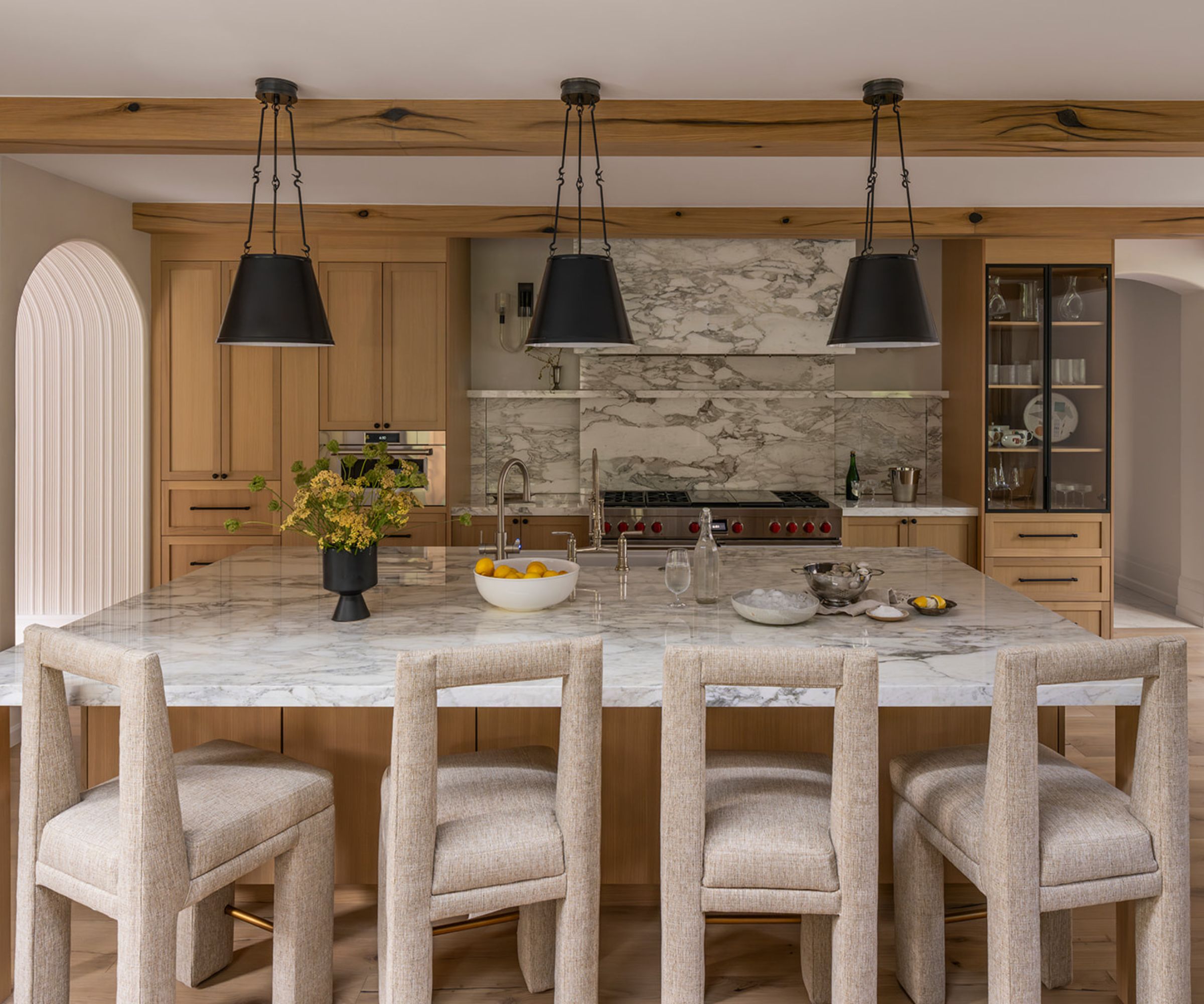 A wooden kitchen with marble countertops and an asymmetrical layout