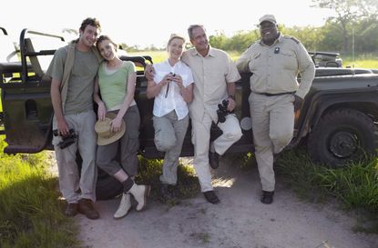 Two couples and ranger by jeep, smiling, portrait