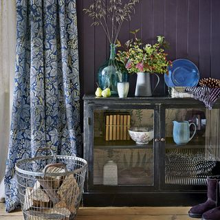 purple hallway with display cabinet floral patterned curtain and log basket