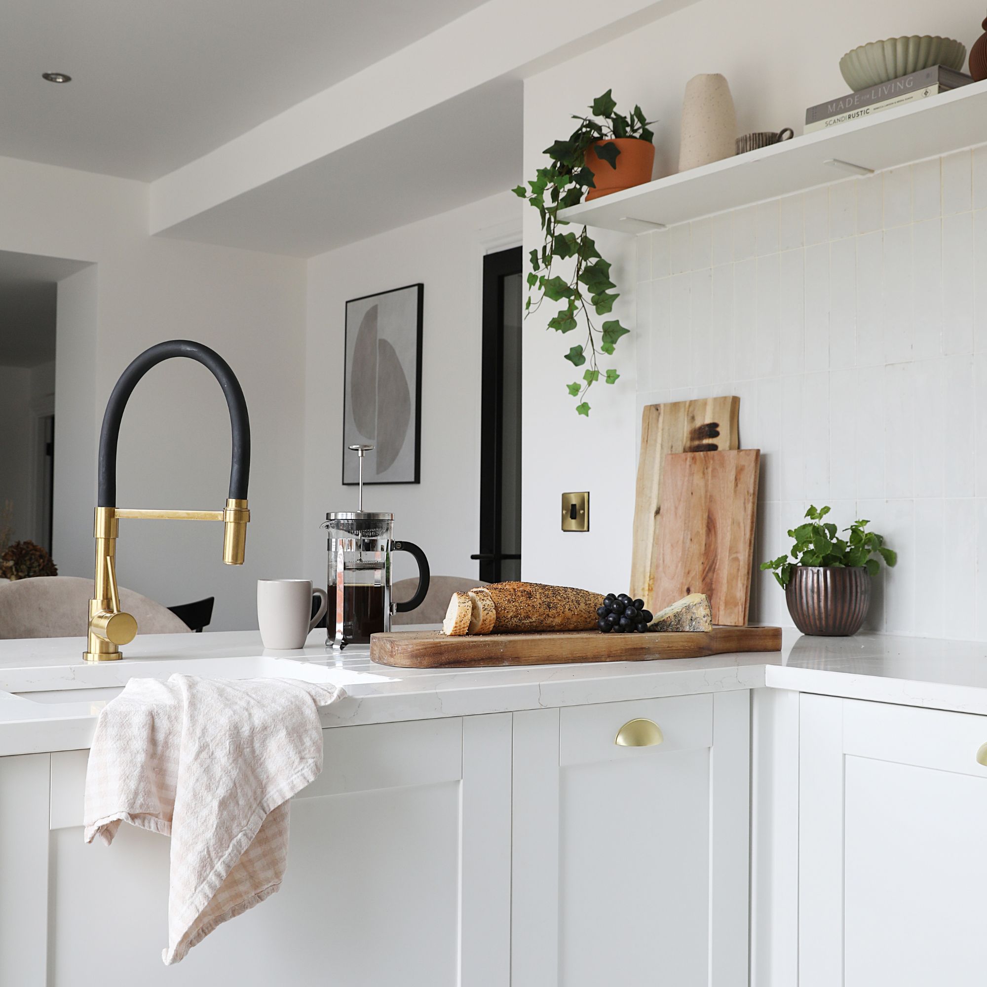 White kitchen with white cabinets and a marble countertop, with black and gold fixings