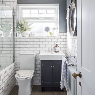 White tiled and blue bathroom with blue vanity unit and white basin above