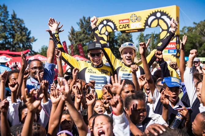 Stage winners and overall yellow jersey leaders Karl Platt and Urst Huber celebrate with local children from the Big Tree Foundation