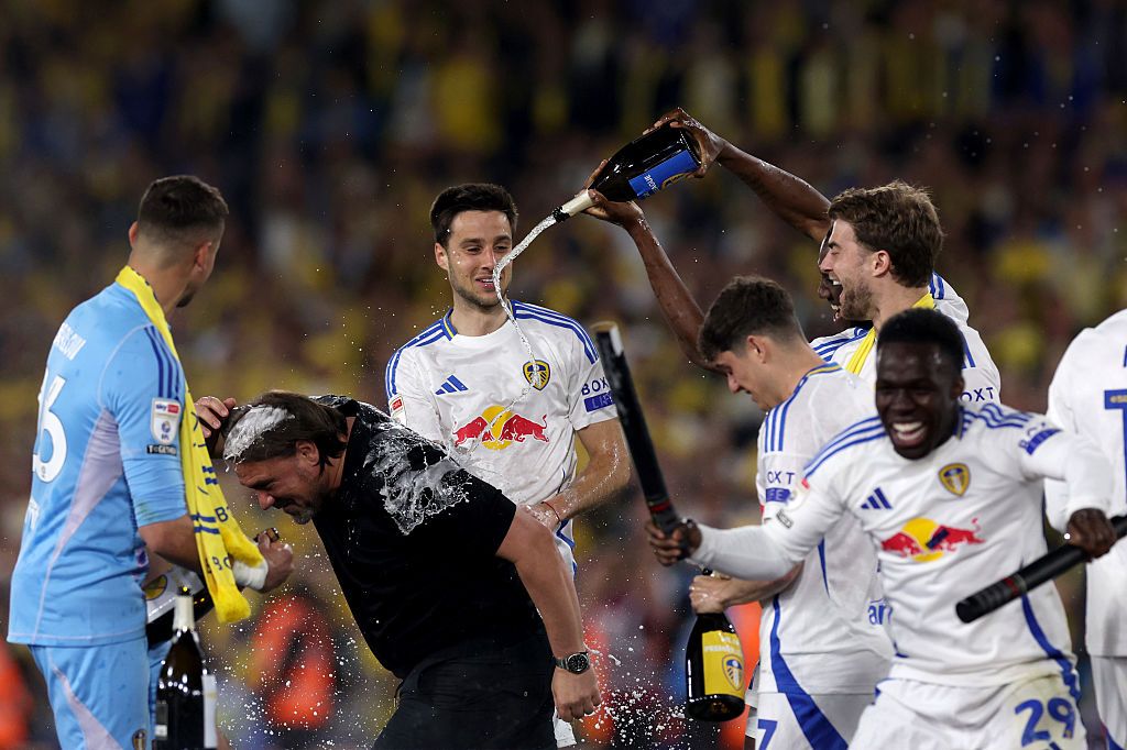 Daniel Farke, Manager of Leeds United, is sprayed by Josuha Guilavogui of Leeds United (partially obscured) as they celebrate promotion to the Premier League at the end of the Sky Bet Championship match between Leeds United FC and Bristol City FC at Elland Road on April 28, 2025 in Leeds, England.