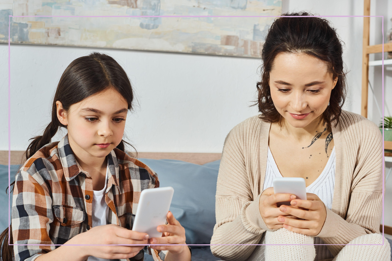 A mother and daughter both looking at their smartphones