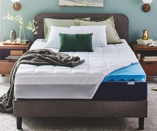A Sleep Innovations Plush Support Dual Layer Gel Memory Foam Mattress Topper on a bed in a modern bedroom
