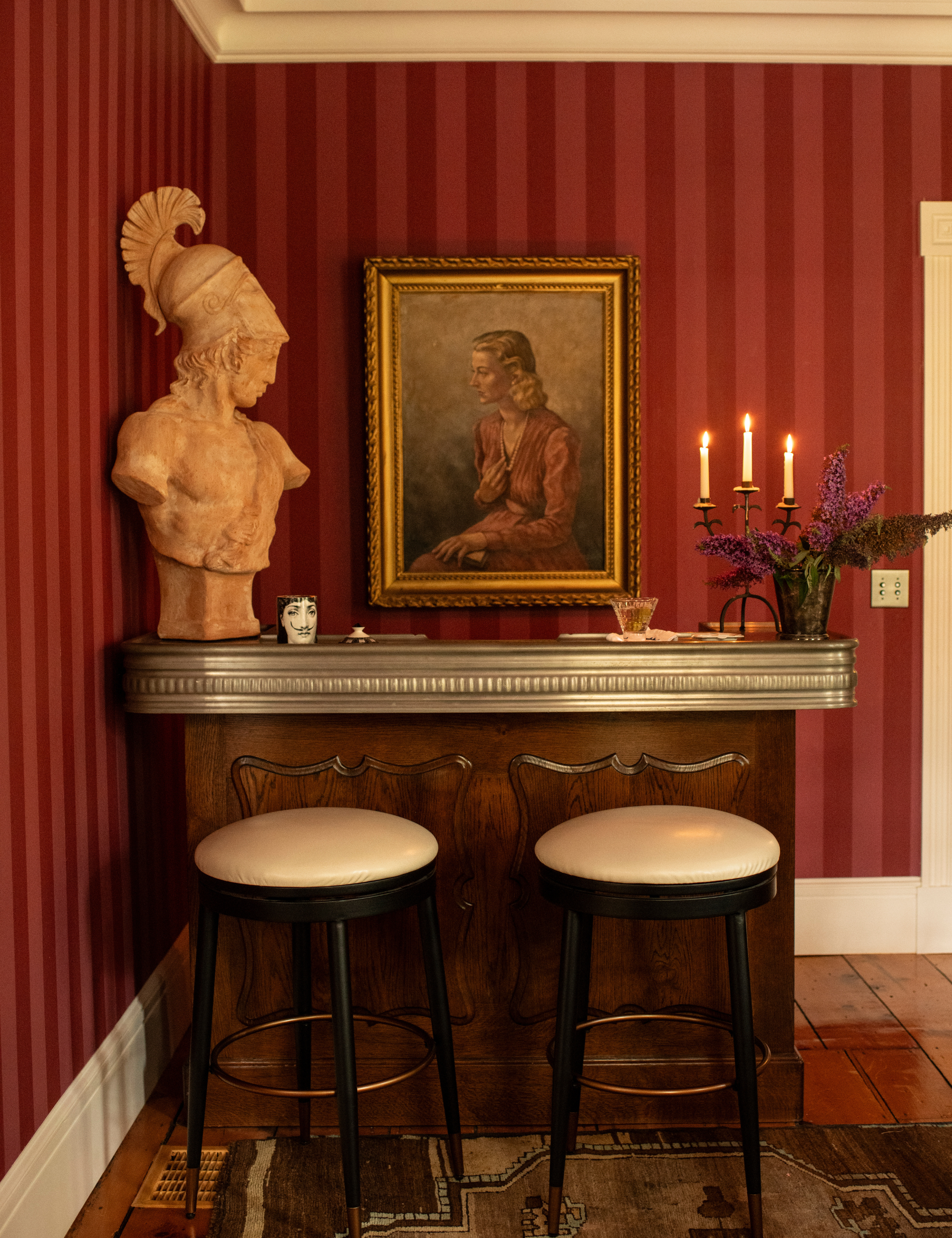 Pink-and-red striped bar area decorated with antique wooden furniture and artwork