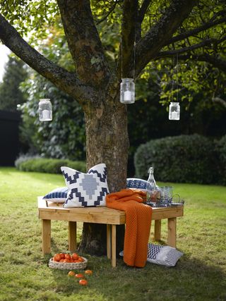 garden bench built around a tree trunk with lanterns hanging from the branches