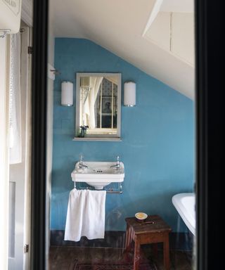 Blue bathroom with freestanding sink and gold mirror