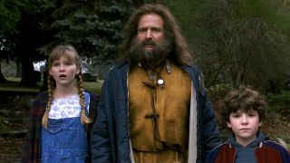 A still of Robin Williams from the 1995 movie Jumanji, in which he's wearing a mustard top and has a long beard.