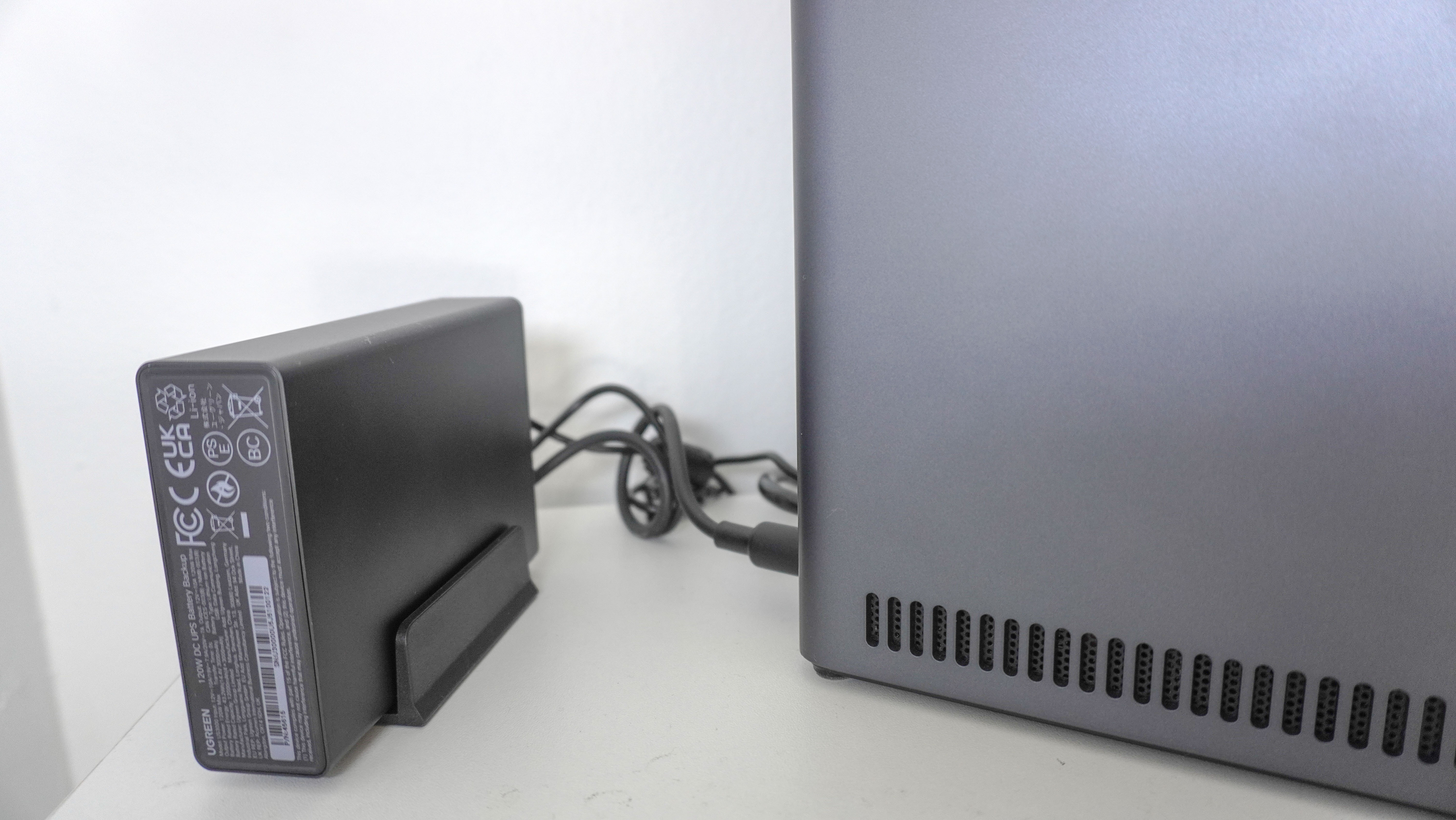 A close-up shot showing the Ugreen US3000 mini UPS connected to a Ugreen NAS