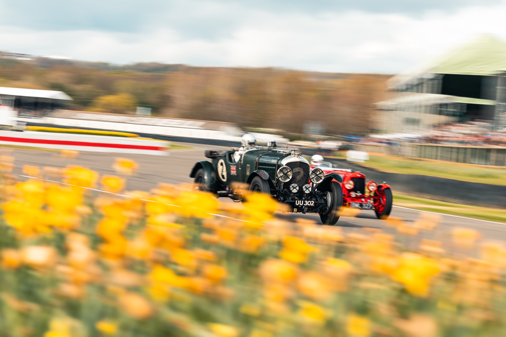 Two vintage racecars fly down the race track