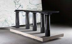 Art installation of five black pillars with a black marble worktop