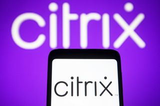 The Citrix logo (the word "Citrix") on a phone against a white background, while in the background the logo is lit up in white text on a purple background.