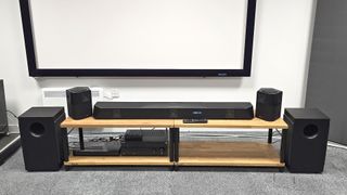 Nakamichi Dragon soundbar system and surrounds on wooden rack with subwoofers on floor to side