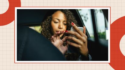 woman with red nails sitting a car typing on her phone