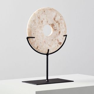 A white marble disc on a black metal stand