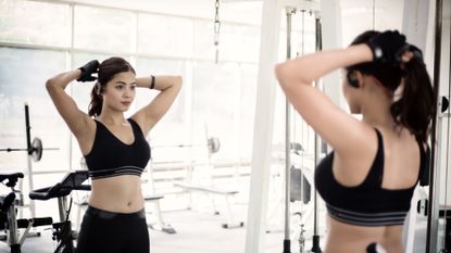 Women looks at herself in the mirror at the gym