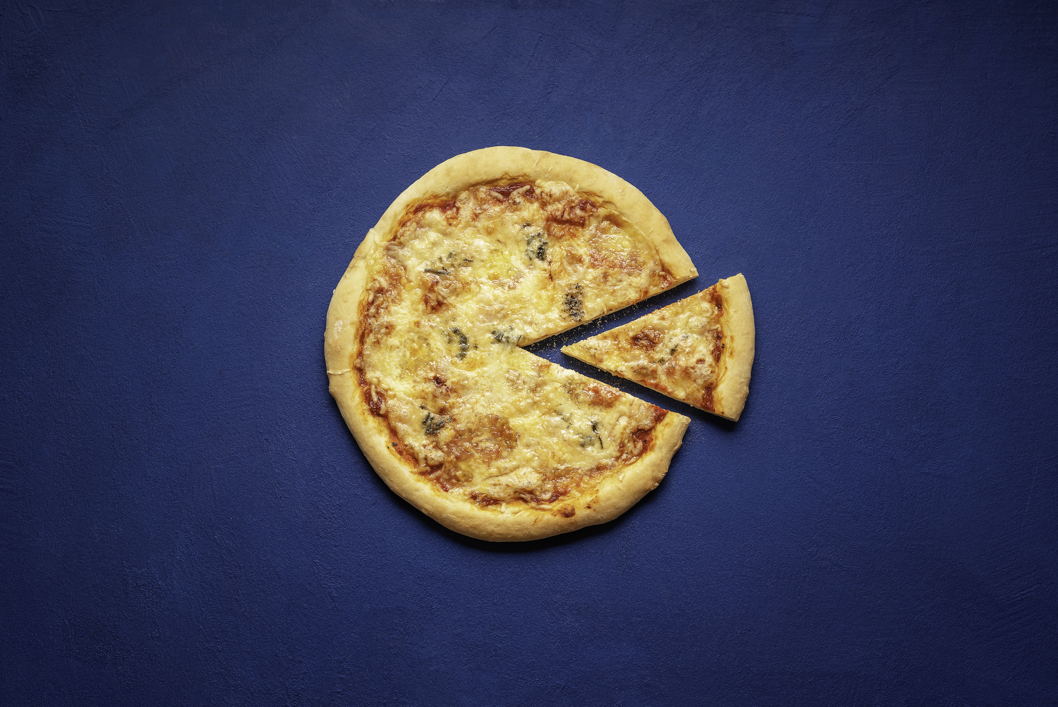 Pizza quattro formaggi made at home. Sliced pizza on a blue background, above view. Italian pizza made with 4 types of cheese.