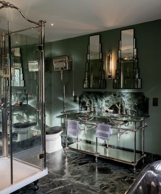 bathroom with dark green marble floors and chrome and green glass topped sink