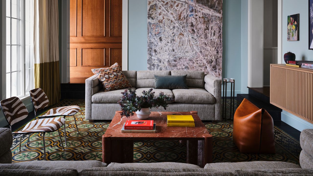 Living room with pale blue walls, grey sofas, red marble coffee table and zebra print chairs