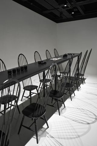 a sloping black dining table, surrounded by a set of 24 matching chairs