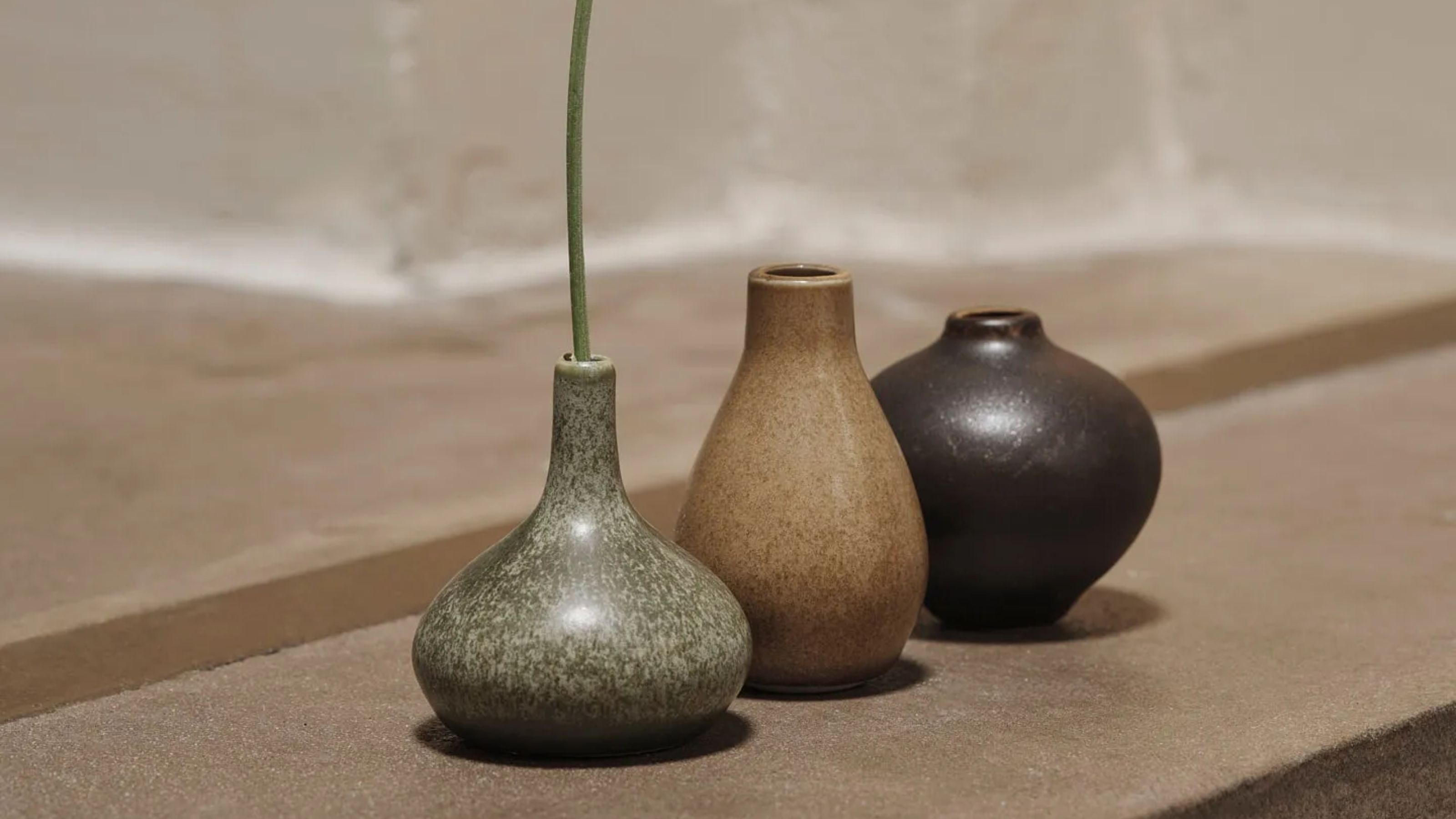 A set of three small Japanese-style bud vases in earthy shades of green, beige, and brown.